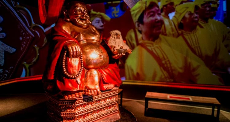 The Flight of the Dragon pre-show area, showing video and a Buddha statue