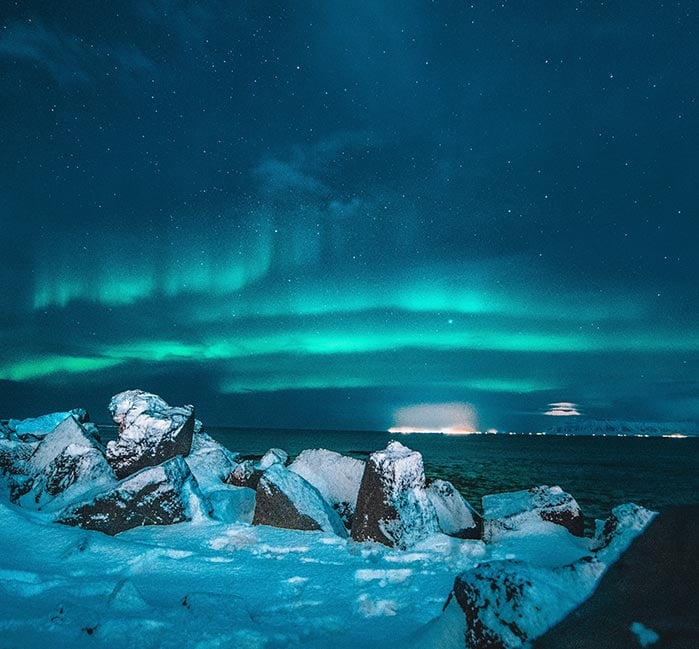 A sheet of ice in water, with green aurora borealis above.