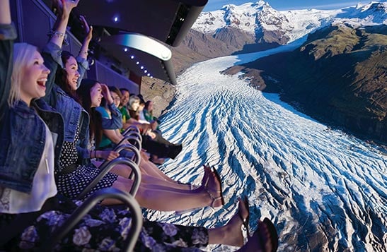 People smile in excitement on the FlyOver Canada flight-ride as big screens show Niagara Falls