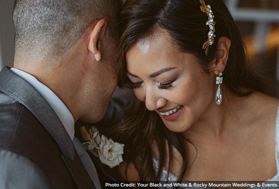 A couple dressed for their wedding lean their heads close together.