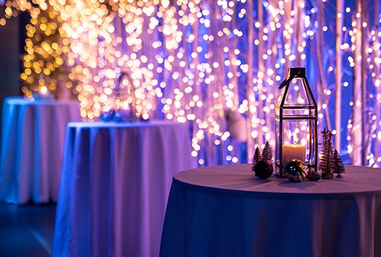 Three cocktail tables in a room decorated with fairy lights and lanterns.
