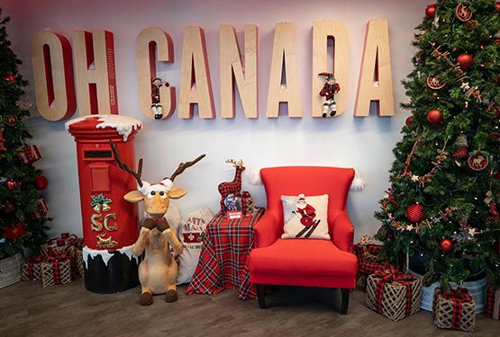 Santa's seat, surrounded by Christmas items and a sign on the wall that says "Oh Canada""