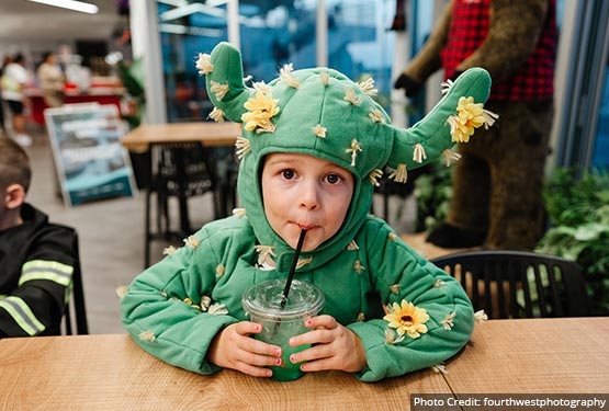 A kid in a green costume with yellow flowers.