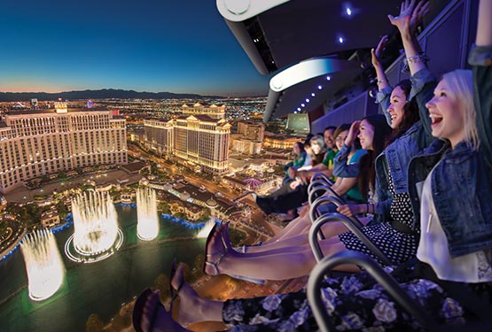 People smiling on a flight ride, superimposed over an aerial view of the Las Vegas Strip.