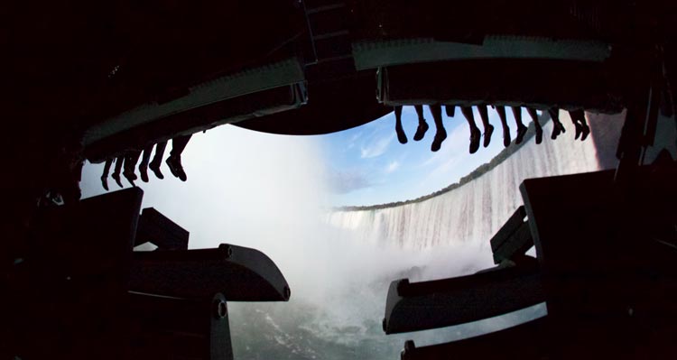 Feet dangle from the FlyOver Canada ride as the screen shows Niagara Falls