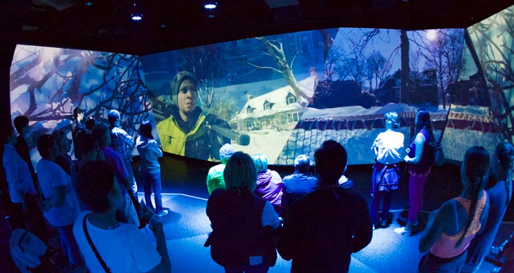 A crowd of people watch an immersive video experience