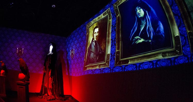 A projection of spooky portraits in a Halloween-decorated room.