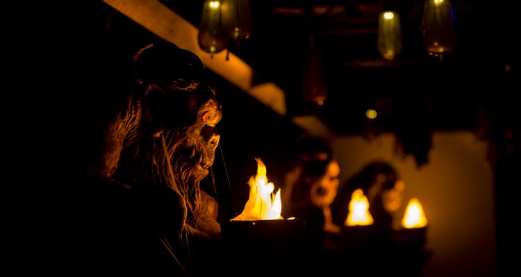 A series of gargoyles and lanterns in a dark room.
