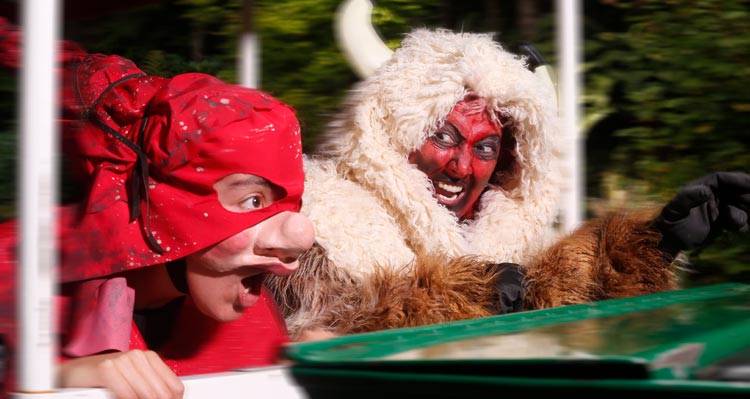 Two costumed people stand upon a green train.