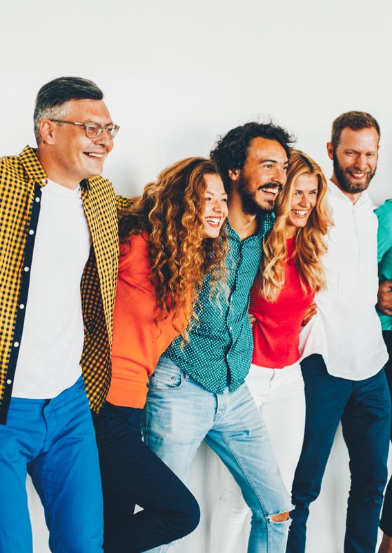 A group of people smile with arms wrapped around each other.