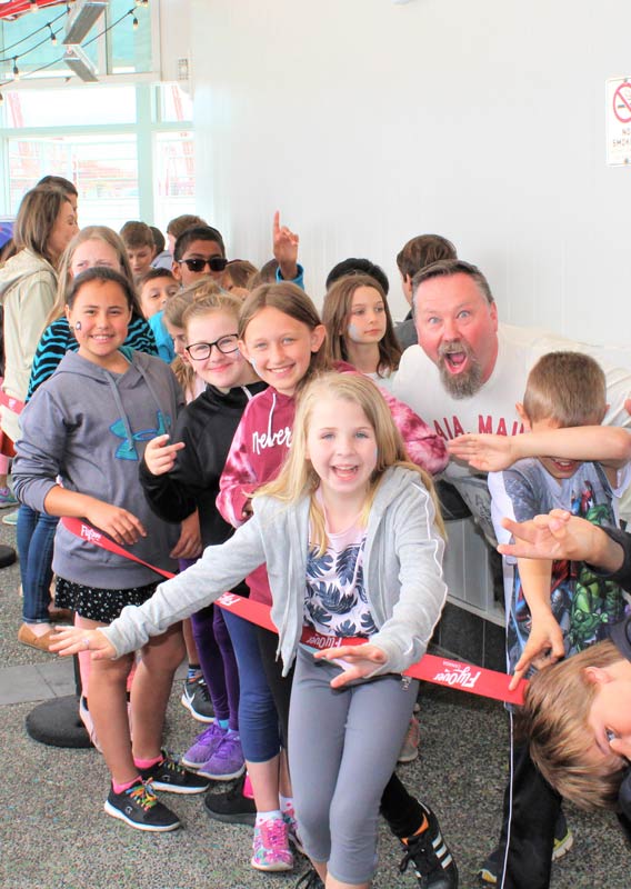 A group of smiling children in the line for FlyOver Canada