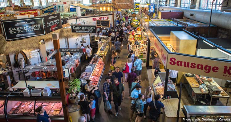 A large indoor market with people shopping at a variety of stalls.