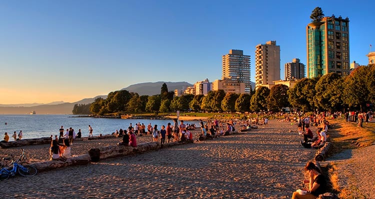 A beach with people relaxing, with the sun setting