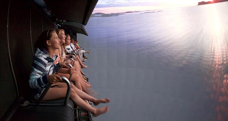A group of kids sit on the FlyOver Canada flight ride.