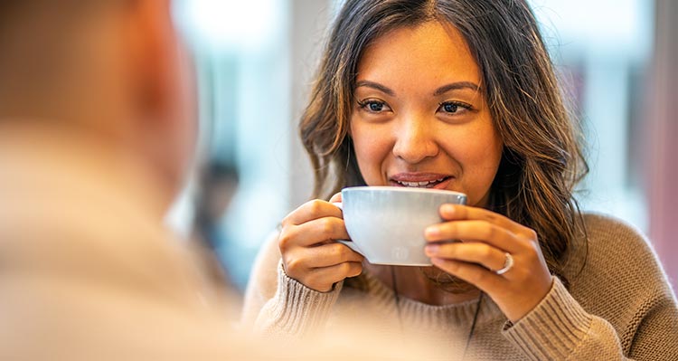 A person holds a cup of coffee up to drink