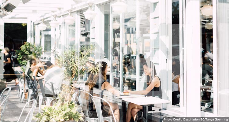 A modern cafe patio with plants in the sun.