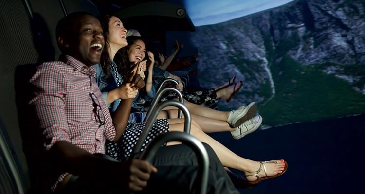 A group of people sit with excitement on the FlyOver Canada flight-ride.