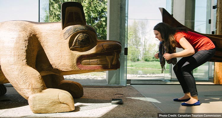 A woman poses next to a sculpture in a museum