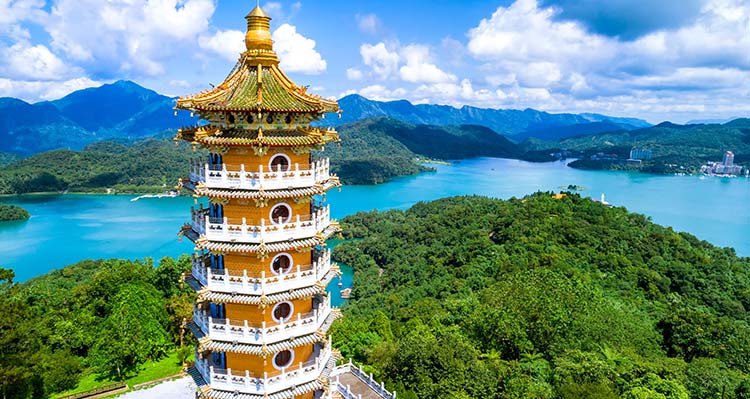 Pa Cien Pagoda above blue water between tree-covered mountains.