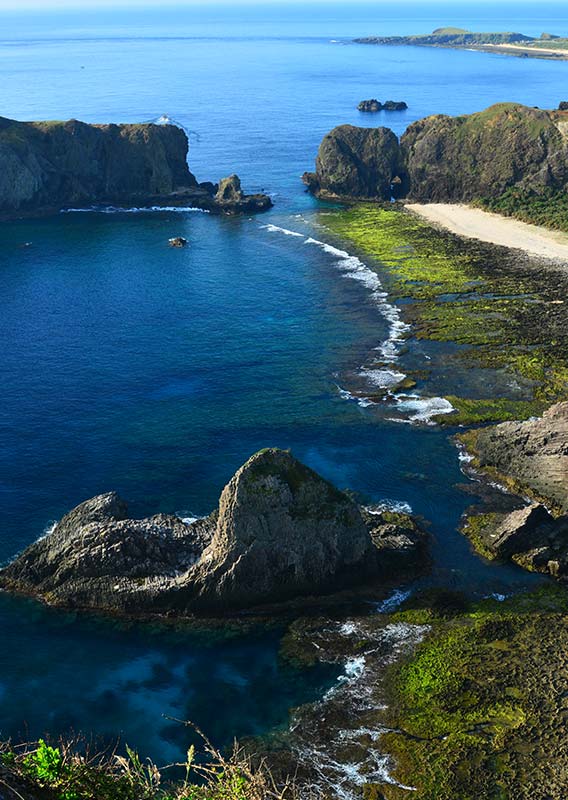 A cliffside seashore above blue ocean water