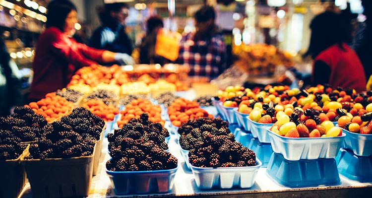 Baskets of berries at a fruit stand in an indoor market.