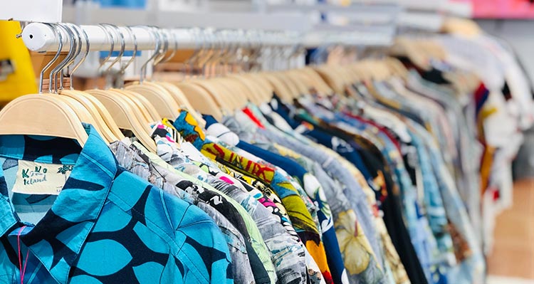 Hawaiian shirts hang on a clothing rack.