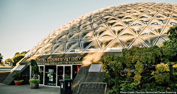 Dome shaped conservatory building at sunset, greenery surrounding.