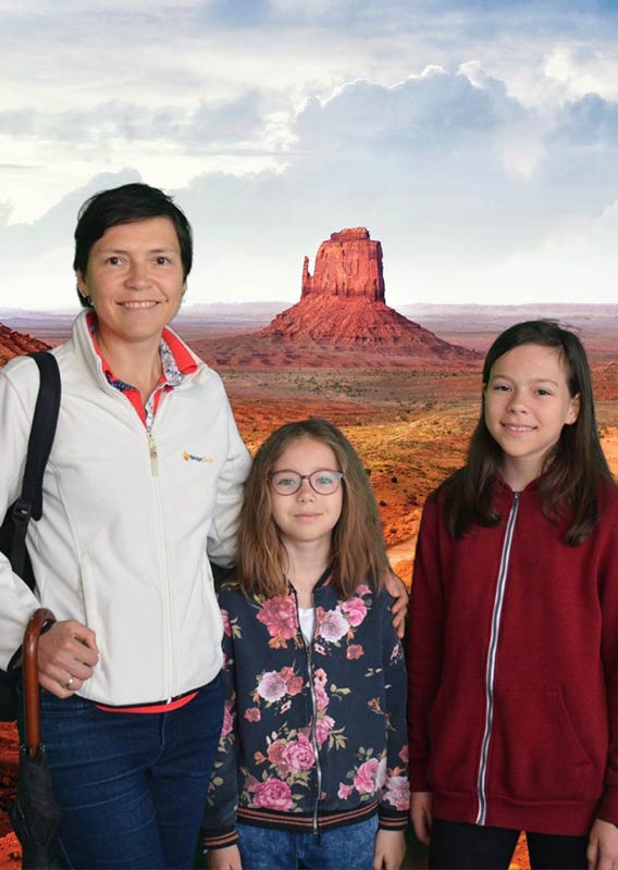 A women and two young girls pose in front of the Real Wild West show background.