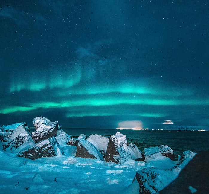 A sheet of ice in water, with green aurora borealis above.