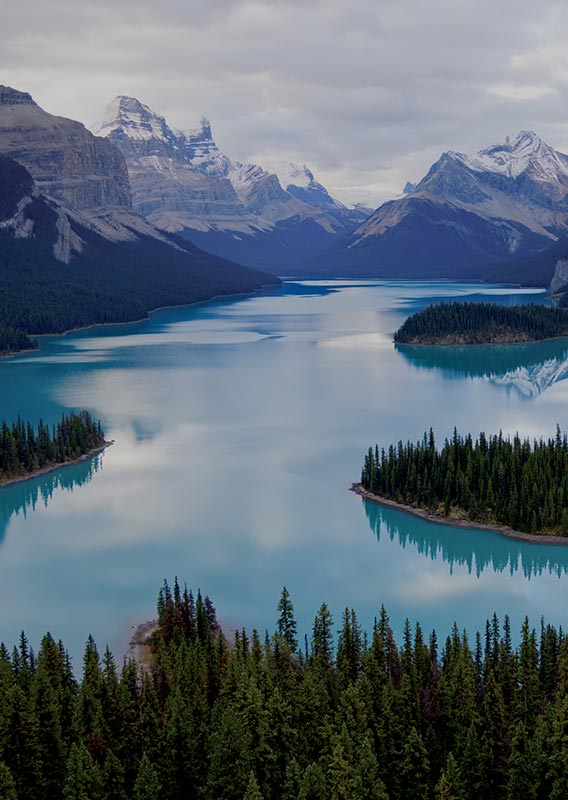 A birds-eye view overlooking a large lake between tall mountains.